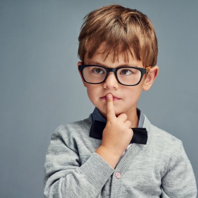 Pensive young boy with his index finger over his mouth